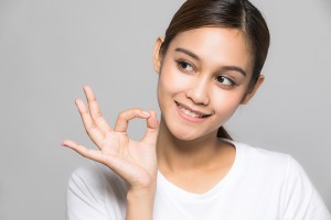 Young woman making OK hand sign.